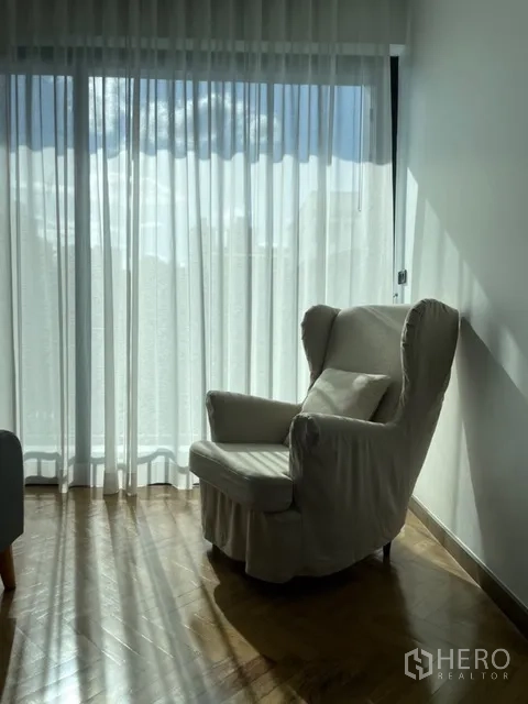 Detached House for rent in Watthana, Bangkok - Cozy armchair by a sunlit window with sheer curtains.