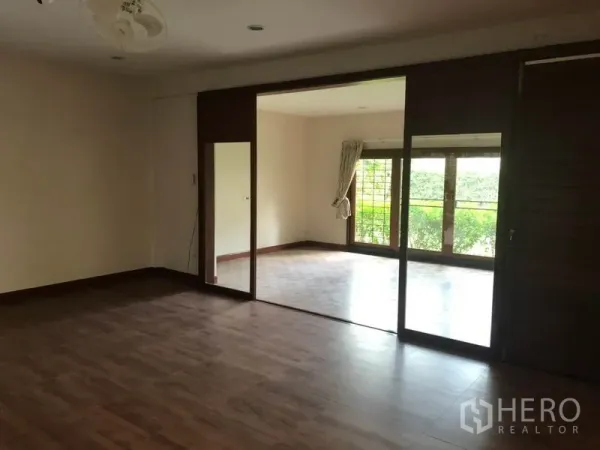 Detached House for rent in Watthana, Bangkok - Spacious living area with wood floors opening to a bright sunroom.