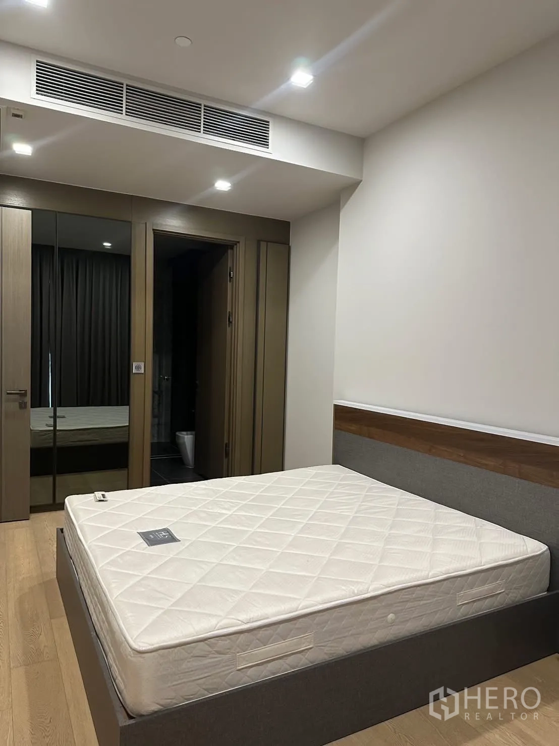 Condominium for rent or sale in Watthana, Bangkok - Second bedroom with bed frame, mirrored wardrobe, and ensuite door.