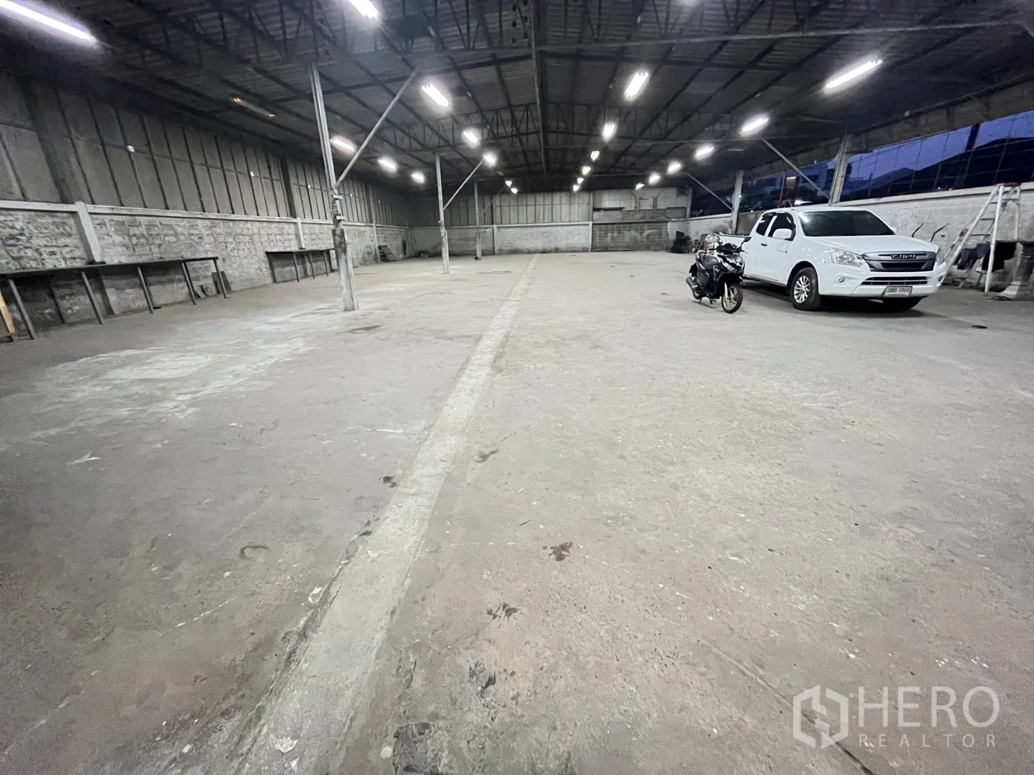 仓库 for rent in Chatuchak, Bangkok - 仓库地面与支撑立柱，可见停放的皮卡与摩托车。
