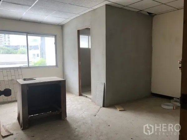 Townhouse for rent in Watthana, Bangkok - Renovation-ready room with a built-in bathroom, big window, and concrete flooring.