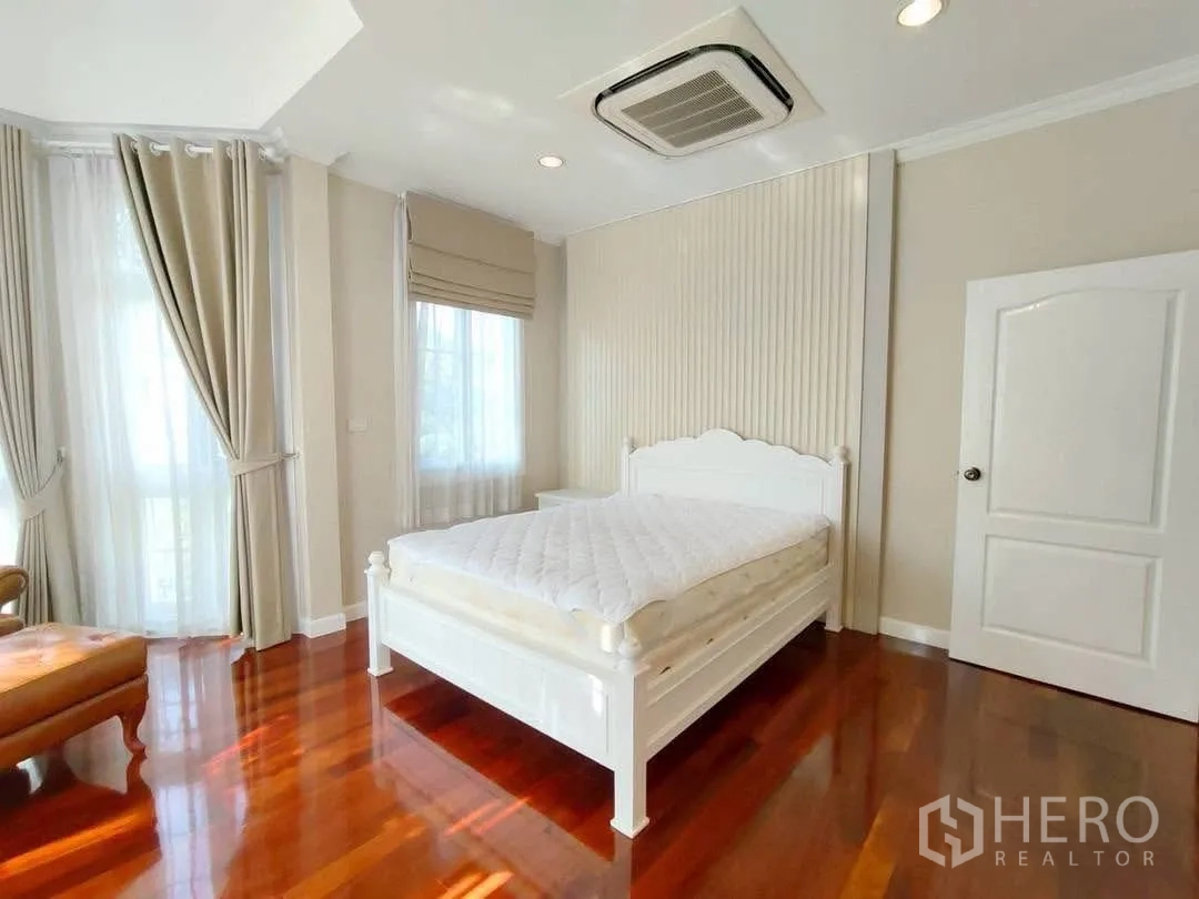 Detached House for rent in Bang Na, Bangkok - Sunlit bedroom with white bed and floor-to-ceiling curtains.