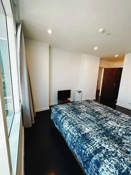 คอนโด ให้เช่าหรือขาย - ห้องนอนพื้นไม้เข้มพร้อมหน้าต่างบานใหญ่และวิวเมือง