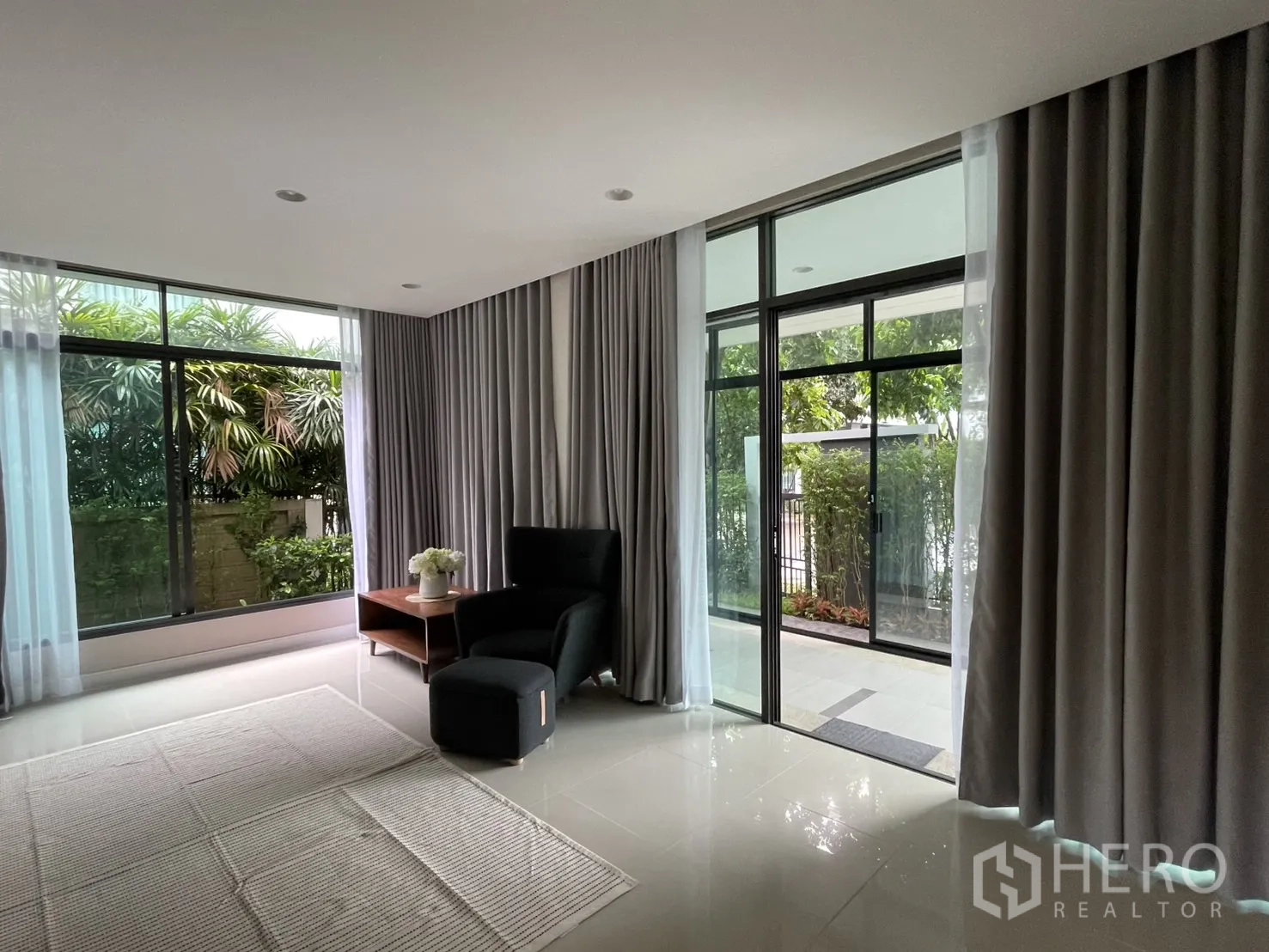 Detached House for rent in Bang Kapi, Bangkok - Living room corner with sliding glass door to the front patio and curtains.