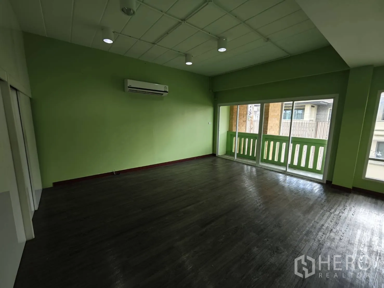 Office Space for rent in Prawet, Bangkok - Green-painted office room with sliding doors to balcony and wall-mounted AC.