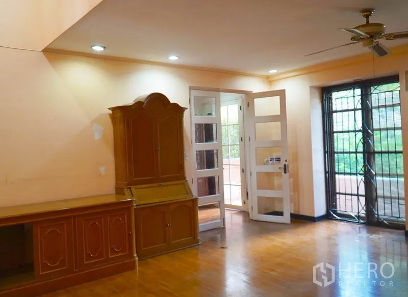 Townhouse for rent in Pathum Wan, Bangkok - Living room with built-in cabinetry, ceiling fan and balcony doors.