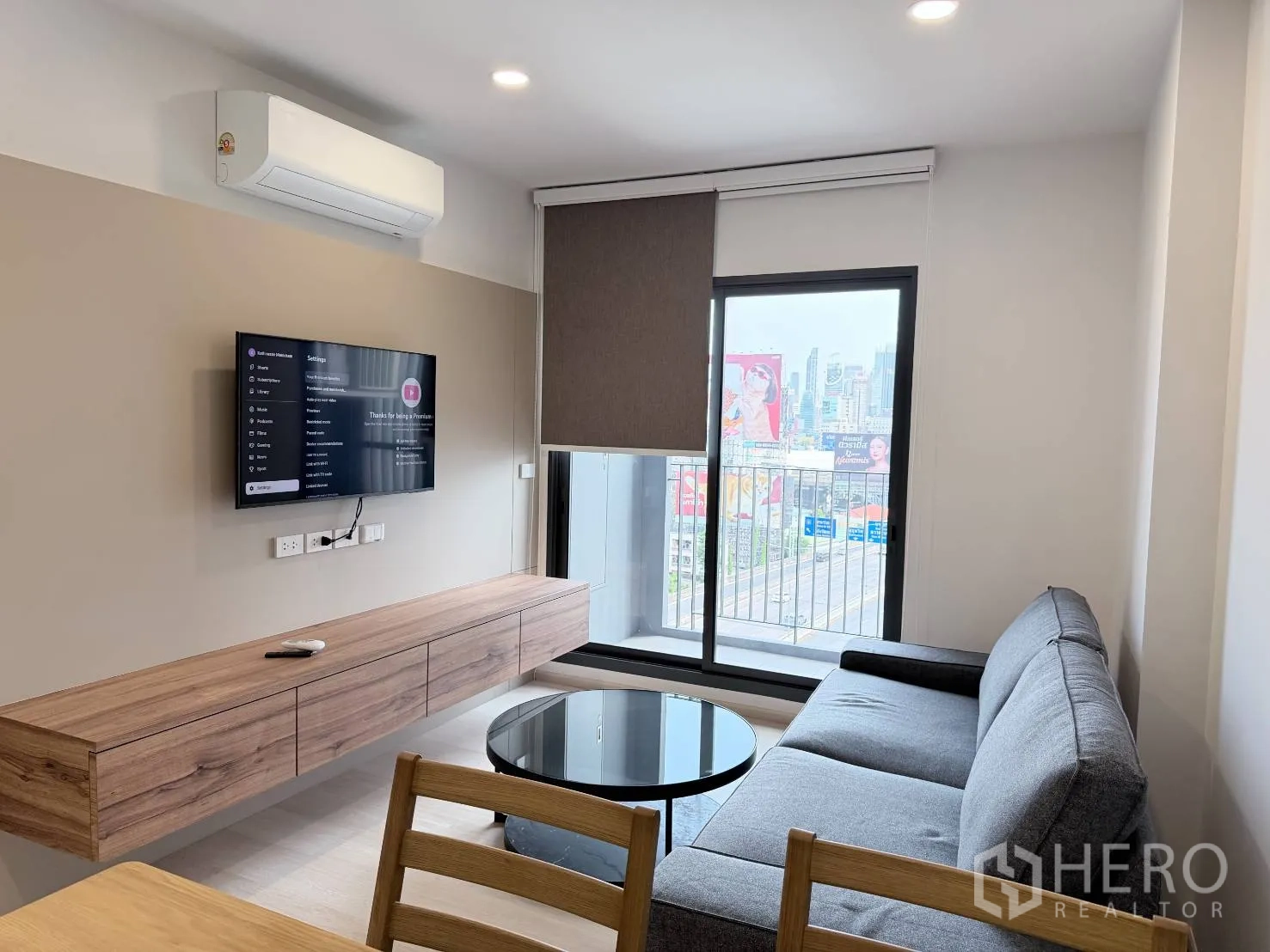 คอนโด for rent in Din Daeng, Bangkok - ห้องนั่งเล่นติดทีวีผนัง เครื่องปรับอากาศ และประตูกระจกสไลด์ออกระเบียงมองวิวเมือง