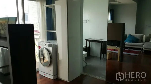 Condominium for rent in Watthana, Bangkok - In-unit laundry corner with a front-loading washing machine beside the bathroom and balcony window.