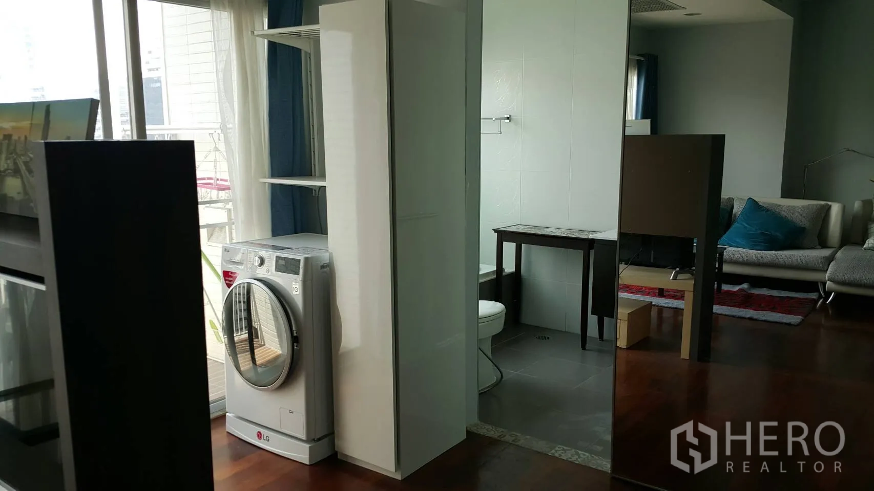 Condominium for rent in Watthana, Bangkok - In-unit laundry corner with a front-loading washing machine beside the bathroom and balcony window.