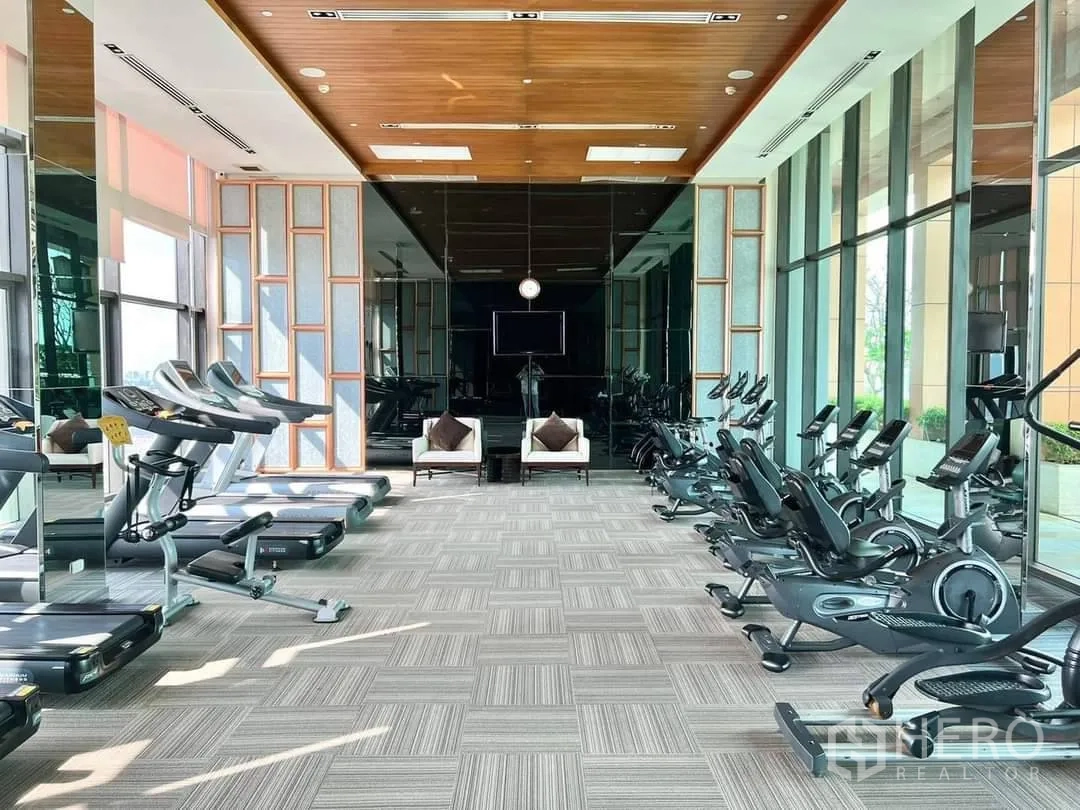Condominium for rent or sale in Bang Rak, Bangkok - Fitness center with treadmills, bikes and floor-to-ceiling windows.