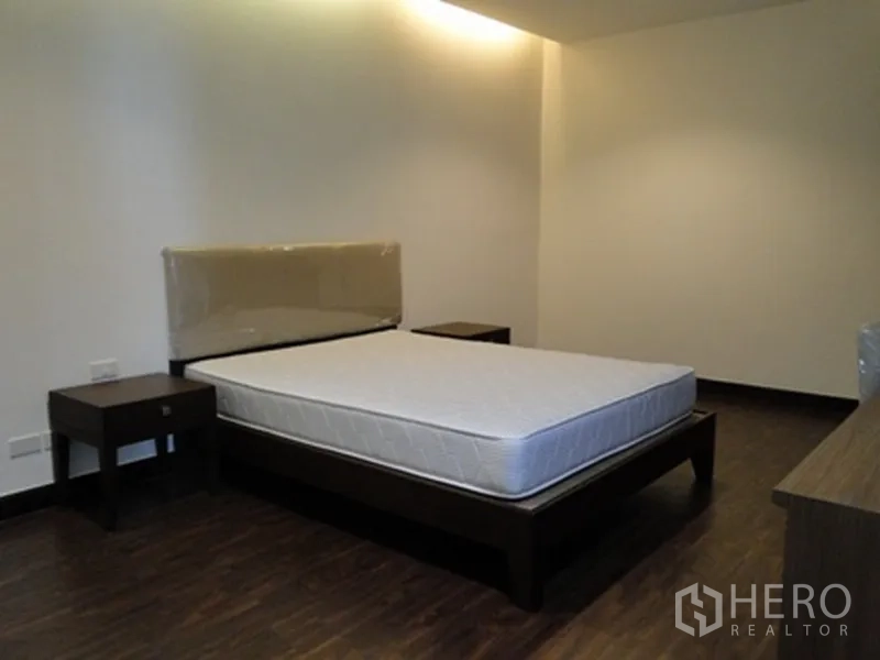 Condominium for rent in Watthana, Bangkok - Cozy bedroom with wooden bedframe, bedside tables, and dark wood floors.
