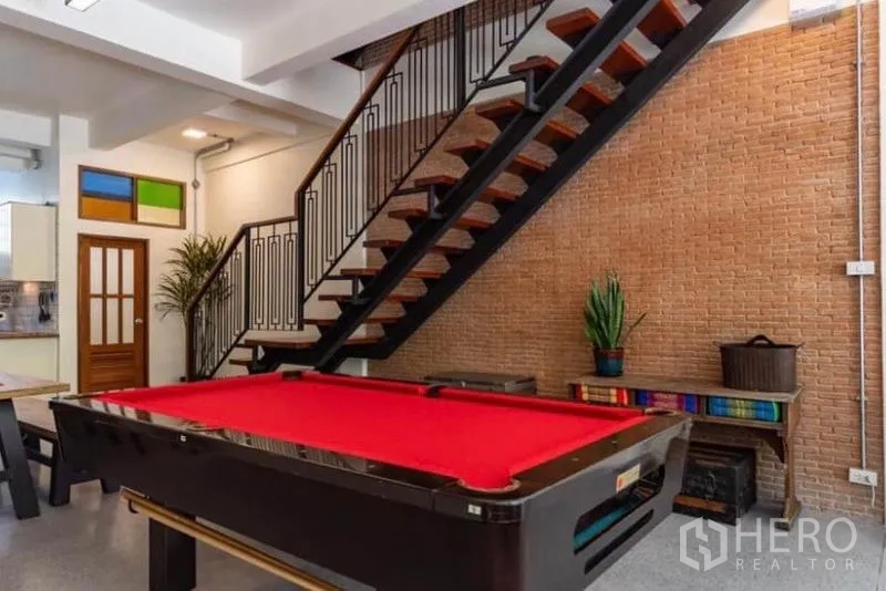 Townhouse for rent in Pathum Wan, Bangkok - Entertainment area with red felt pool table beside an open steel staircase.