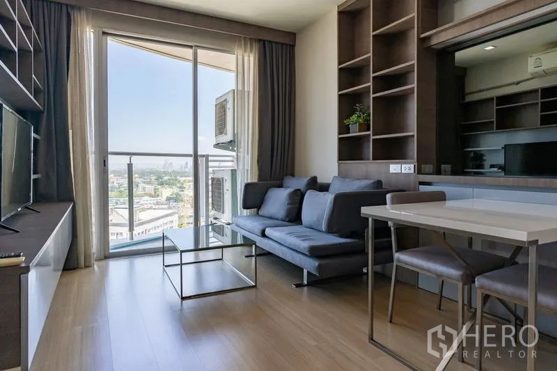 Condominium for rent - Living area with gray sofa, dining table and sliding glass door opening to the balcony.