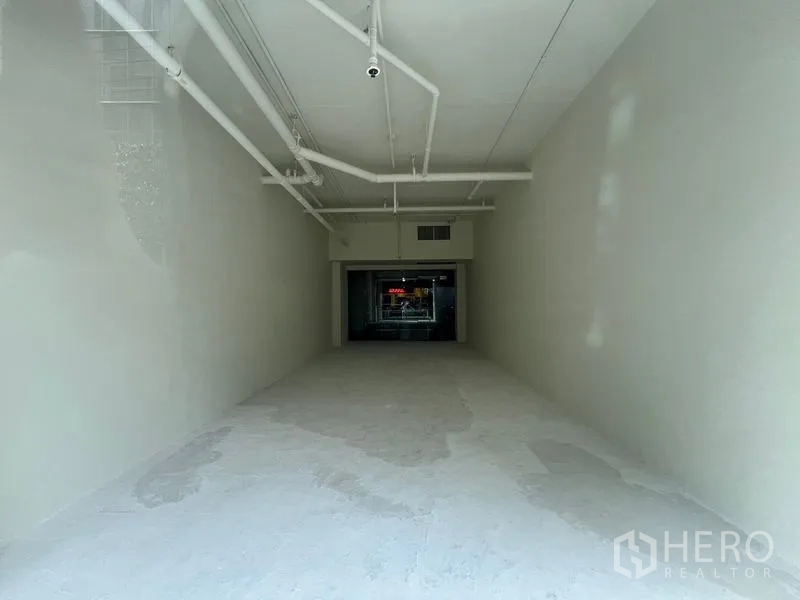 零售空间 出租在Watthana, Bangkok - 由入口回望，白盒内部与商场走廊一览无遗。