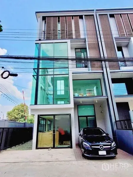 Home Office for sale in Wang Thonglang, Bangkok - Modern three-storey home office with glass corner facade and car parking in front.