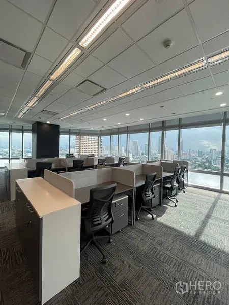 Office Space for rent in Dusit, Bangkok - Corner open-plan office with bench desks, rolling chairs and wraparound windows.