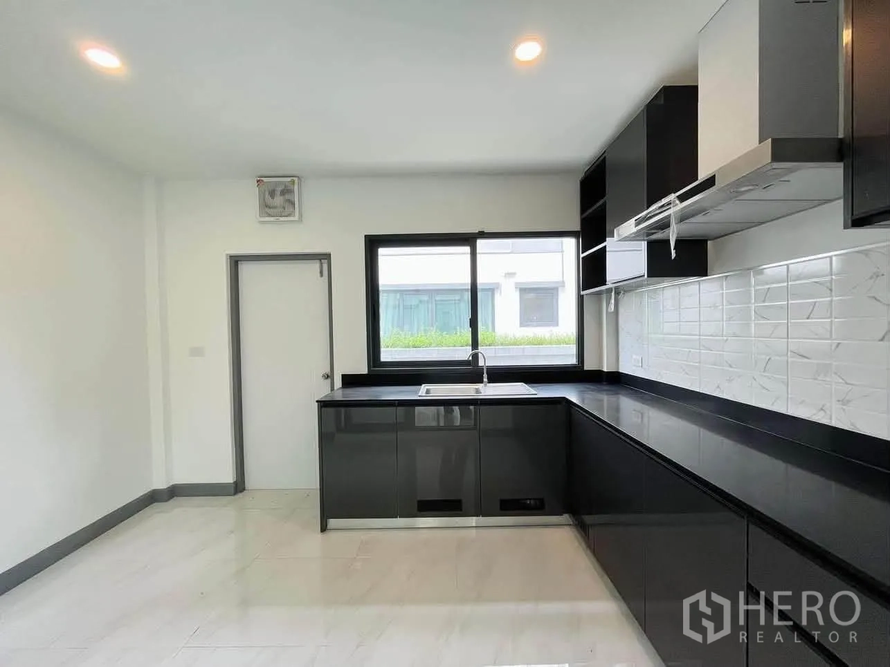 บ้านเดี่ยว for rent or sale in Prawet, Bangkok - ครัวสว่างเคาน์เตอร์สีดำ อ่างล้างจานใต้หน้าต่าง และพื้นกระเบื้องเงา