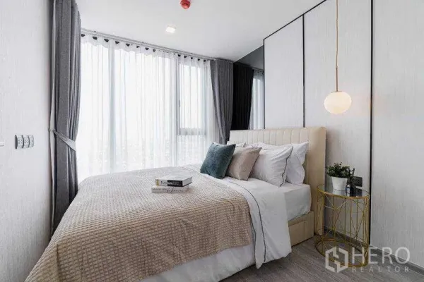 Condominium for rent in Phra Khanong, Bangkok - Bright master bedroom with floor-to-ceiling windows, sheer curtains, pendant light and built-in wardrobe in a Phra Khanong condo.