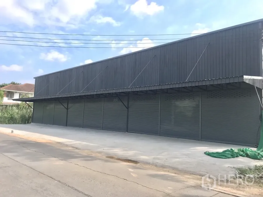 คลังสินค้า ให้เช่าในLam Luk Ka, Pathum Thani - โกดังสีเทาทันสมัยพร้อมประตูม้วนหลายบานและลานคอนกรีตกว้างหน้าถนน