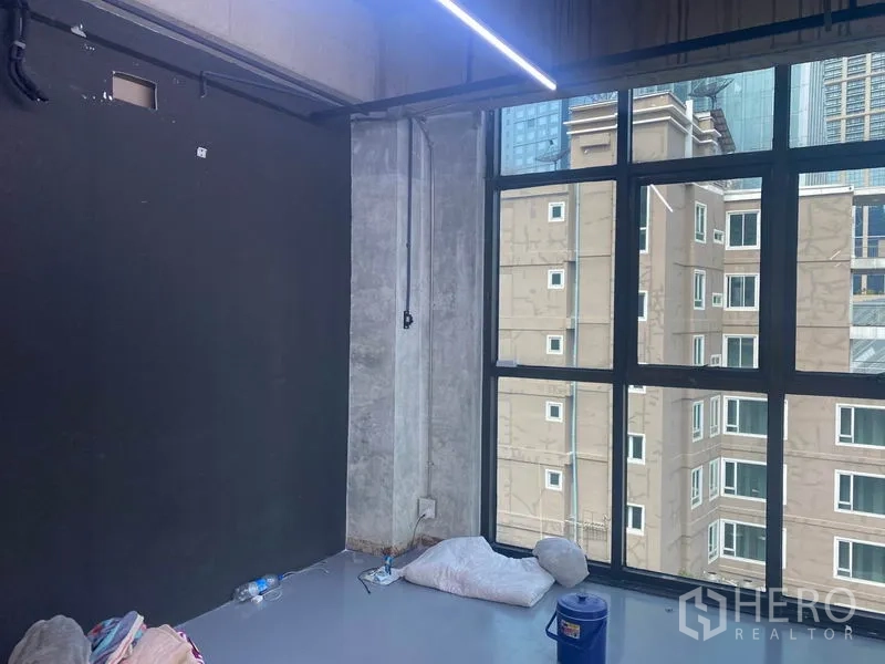 สำนักงาน ให้เช่าในKhlong Toei, Bangkok - พื้นที่มุมออฟฟิศสไตล์อินดัสเทรียล กระจกสูงจรดเพดาน พื้นขัดมัน และผนังสีดำ มองเห็นอาคารข้างเคียง.