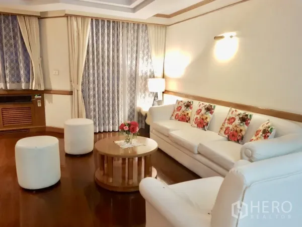 คอนโด ให้เช่าในWatthana, Bangkok - ห้องนั่งเล่นอบอุ่น โซฟาสีขาว โต๊ะกลางทรงกลม และผ้าม่านยาว