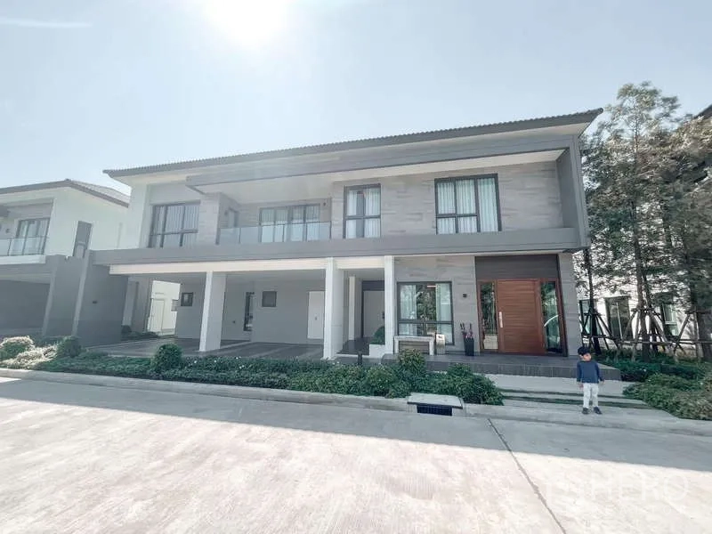 Detached House for rent or sale in Bang Phli, Samut Prakan - Front exterior of a modern two-storey detached house with covered parking and balcony in a gated estate.