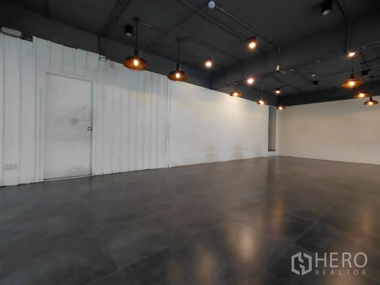 零售空间 for rent in Ratchathewi, Bangkok - 白色墙面与工业风吊顶，暖色吊灯营造氛围的零售空间。