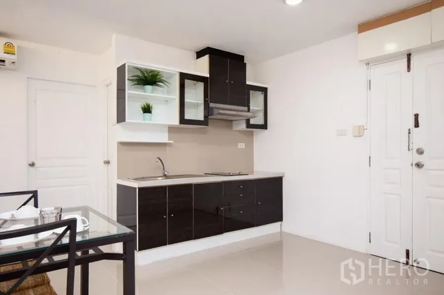 คอนโด ให้เช่าในKhlong Toei, Bangkok - ครัวขนาดกะทัดรัด ตู้หน้าบานสีดำ เตา เครื่องดูดควัน และชั้นเปิด ใกล้ประตูเข้า