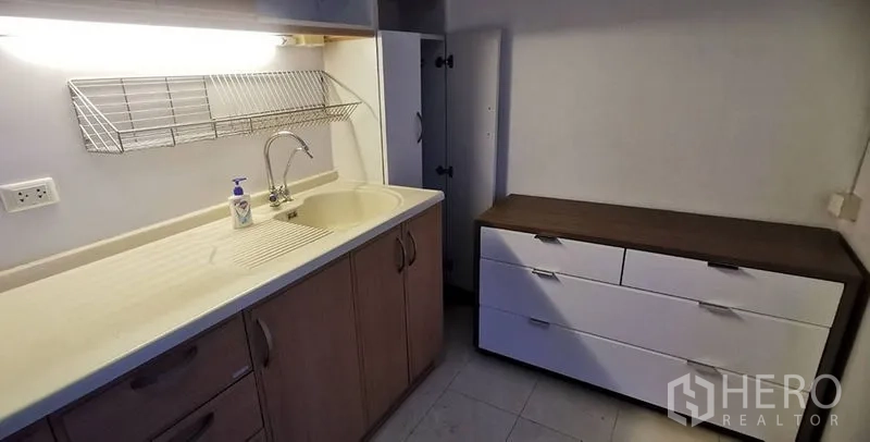 Condominium for rent in Watthana, Bangkok - Kitchen counter with sink, under-cabinet lighting, cabinets, and drawers.