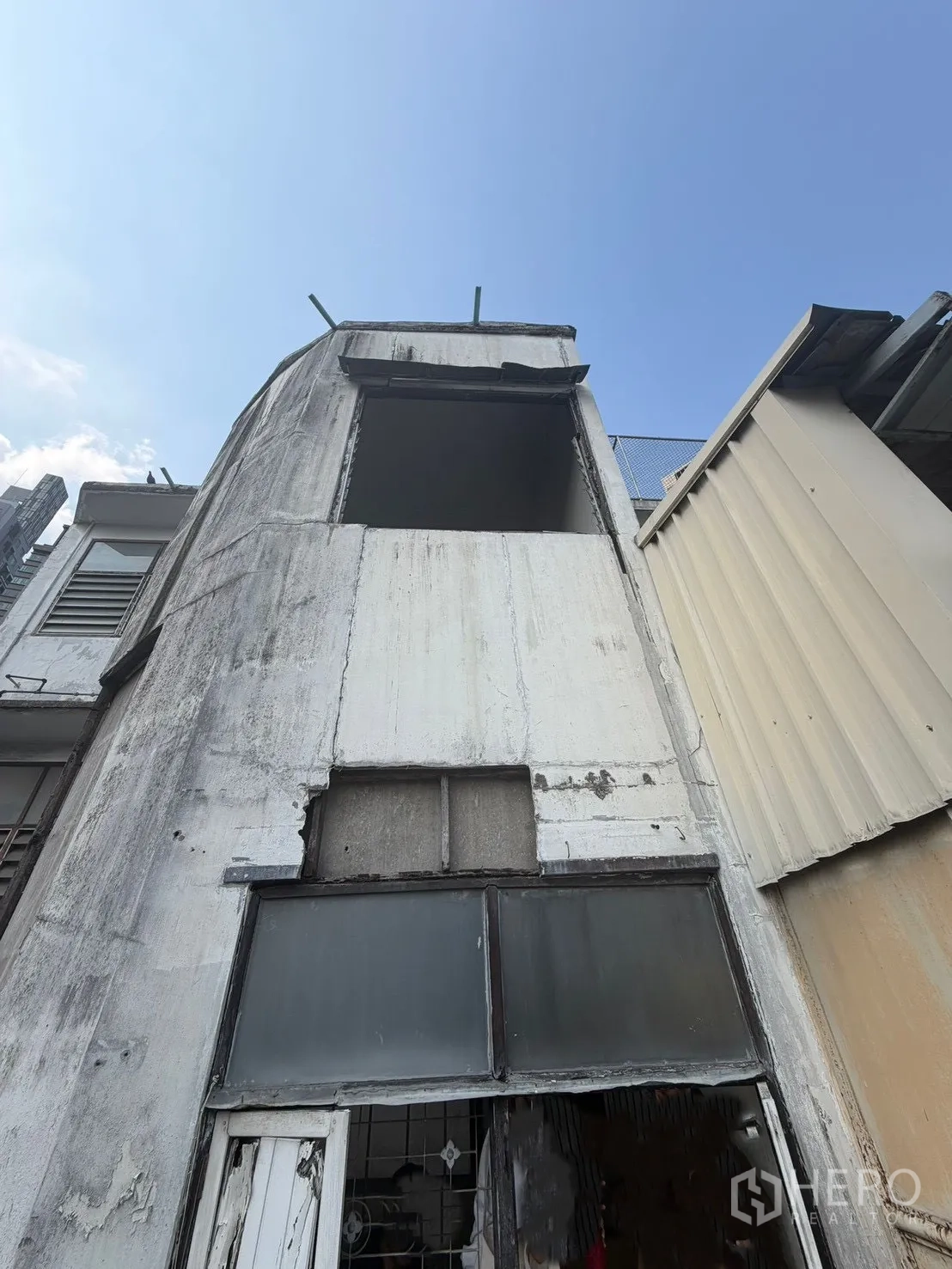 Shophouse for rent in Watthana, Bangkok - Rear exterior facade in worn condition with an open upper window.