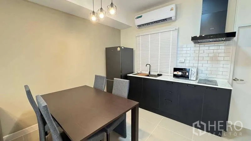 Townhouse for rent in Bang Phli, Samut Prakan - Modern kitchenette with black cabinets, white subway tiles and dining table.