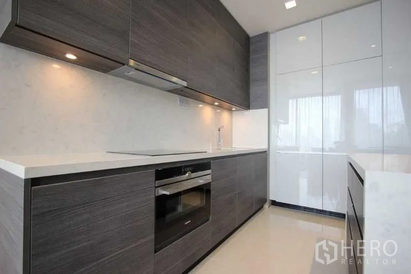 Condominium for rent in Watthana, Bangkok - Sleek fitted kitchen with grey cabinetry, built-in oven and white quartz countertops.