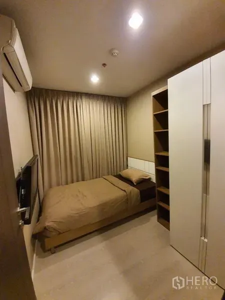 Condominium for rent in Sathon, Bangkok - Cozy second bedroom with single bed, wardrobe, open shelving and blackout curtains.