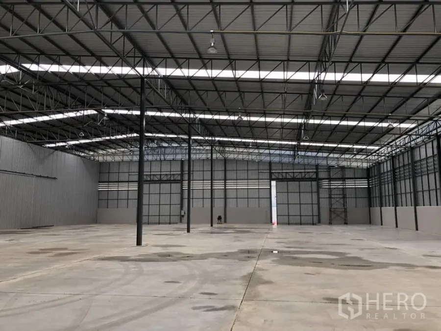 货栈 出租在Lat Krabang, Bangkok - 曼谷Lat Krabang宽敞仓库内部，高钢桁架屋顶、采光带、宽阔混凝土地面与大型滑动门。