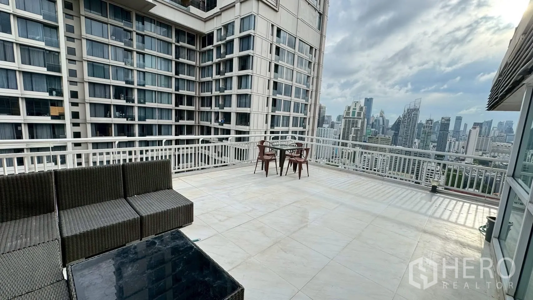 Condominium for rent or sale in Watthana, Bangkok - Large rooftop-style terrace with seating, railings and high-rise city backdrop.
