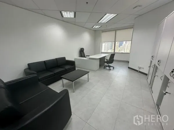 Office Space for rent - Executive office with black leather sofas, white desk, lockers and wide city-view windows.