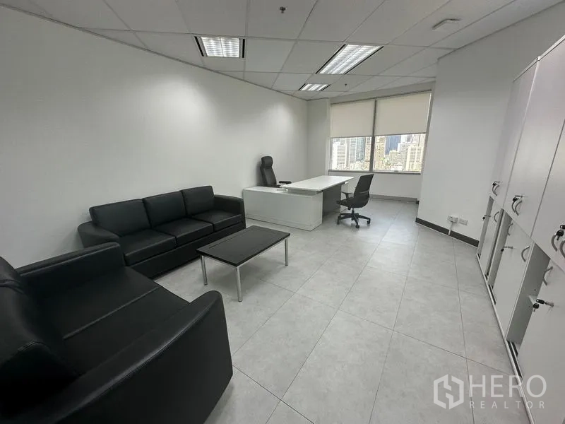 Office Space for rent - Executive office with black leather sofas, white desk, lockers and wide city-view windows.