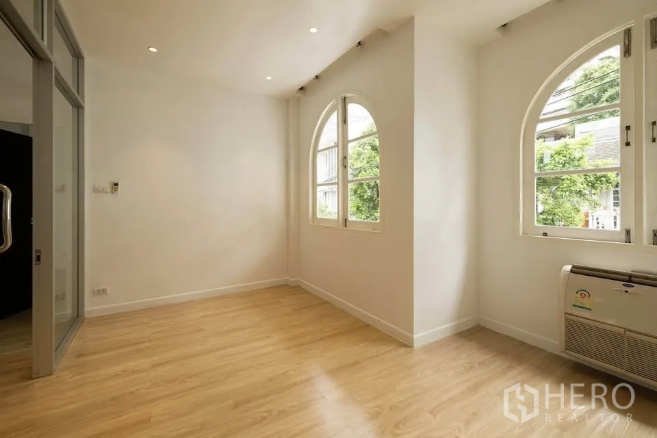 联排别墅 出租在Khlong Toei, Bangkok - 转角卧室，双拱形窗、木地板与壁挂式空调。