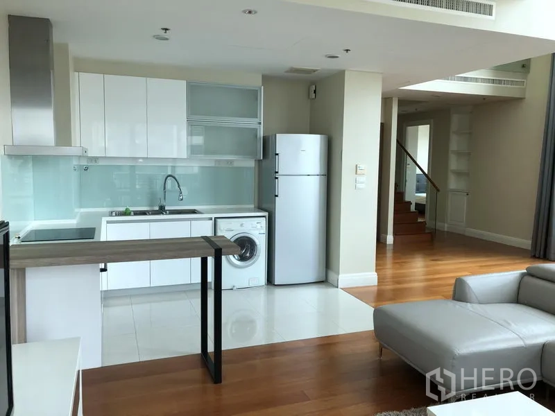 คอนโด ให้เช่าหรือขายในKhlong Toei, Bangkok - ครัวบิวท์อินสีขาวพร้อมตู้เย็น เครื่องซักผ้า และเคาน์เตอร์บาร์ ข้างบันได