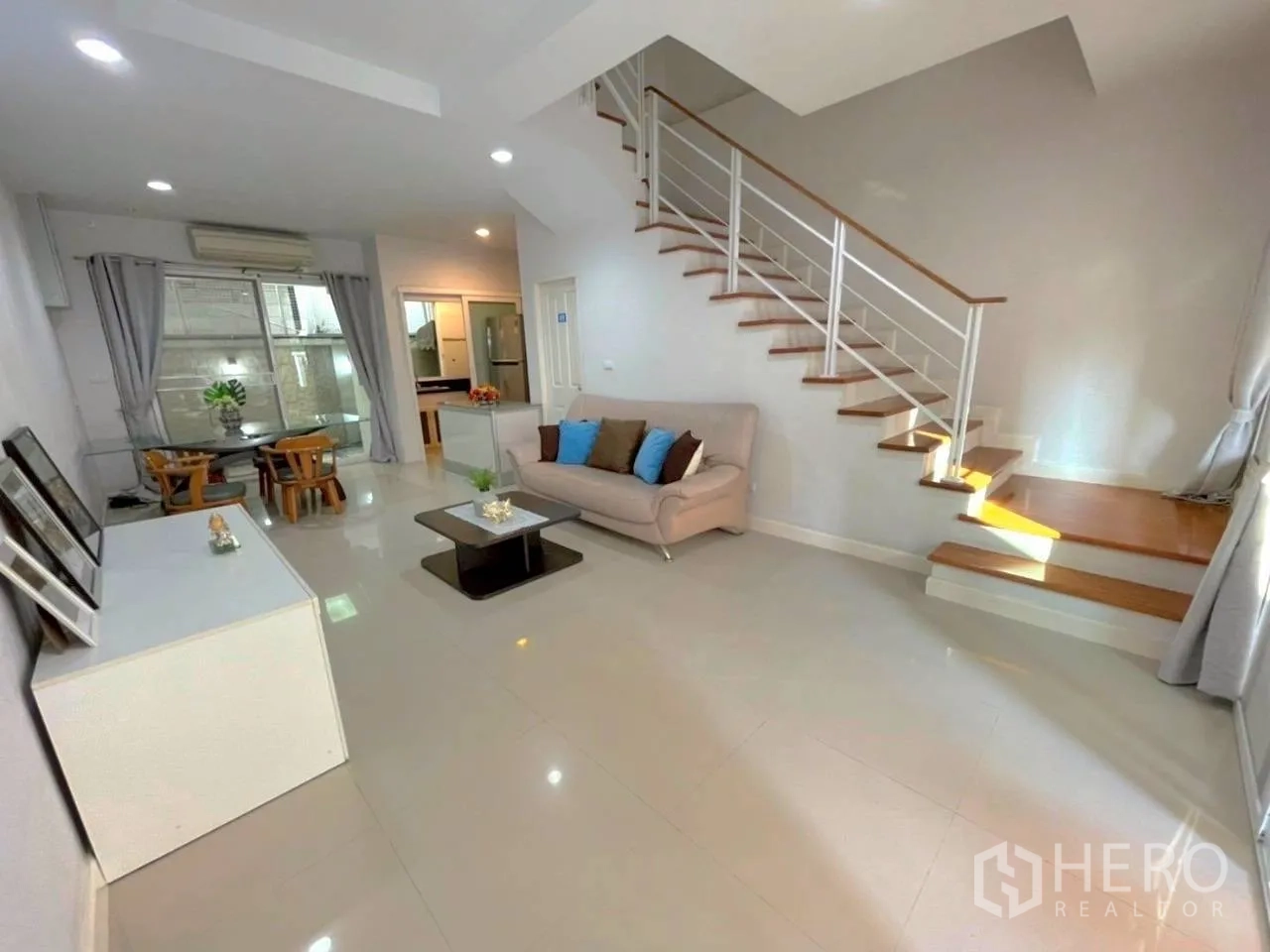 联排别墅 for rent in Bang Kho Laem, Bangkok - 宽阔起居区配沙发、茶几与嵌灯下的楼梯。