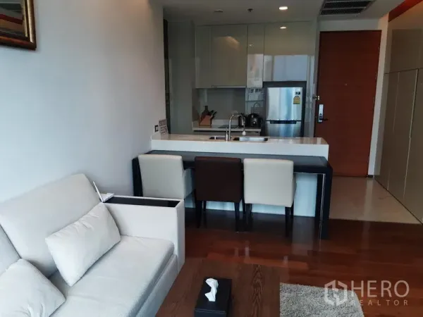 公寓 出租在Khlong Toei, Bangkok - 紧凑现代厨房设中岛吧台、嵌入式柜体与不锈钢冰箱，旁接舒适起居区。