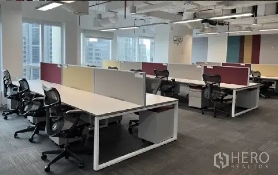 Office Space for rent - Bright office workspace with partitioned desks, carpet tiles and city skyline views through large windows.