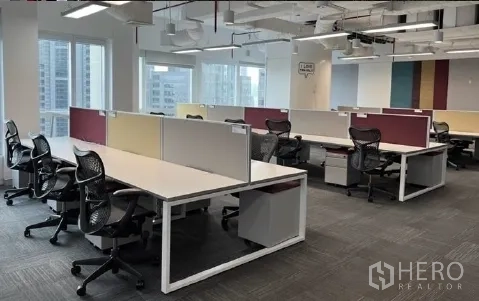 Office Space for rent - Bright office workspace with partitioned desks, carpet tiles and city skyline views through large windows.