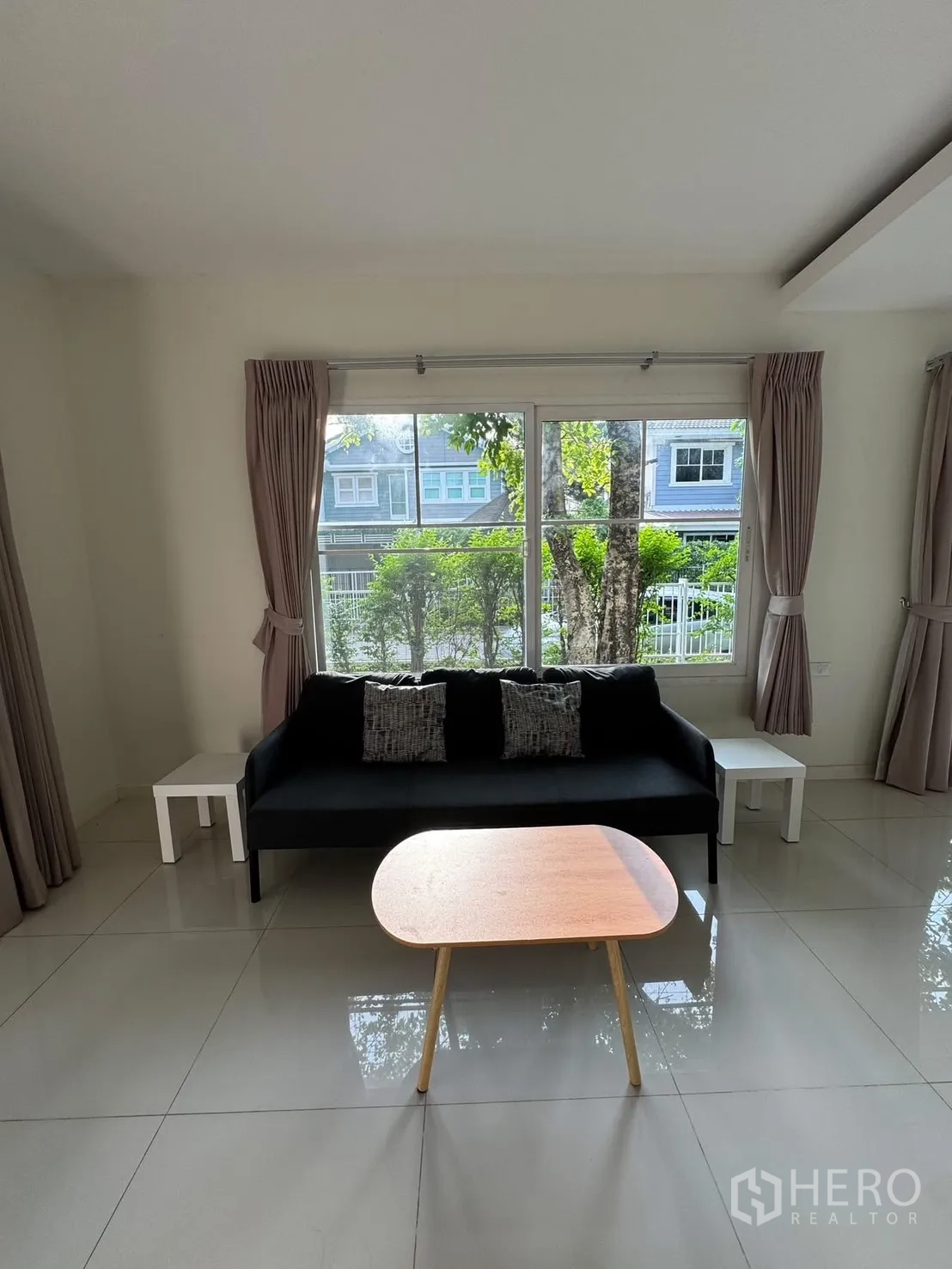 Detached House for rent in Bang Phli, Samut Prakan - Living room with sofa, coffee table, curtains and garden view window.