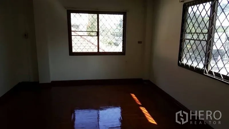 Detached House for rent in Khlong Toei, Bangkok - Corner bedroom with two windows, natural light and hardwood flooring.