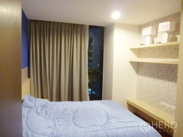 Condominium for rent in Watthana, Bangkok - Second bedroom with single bed, floor-to-ceiling window and floating display shelves.
