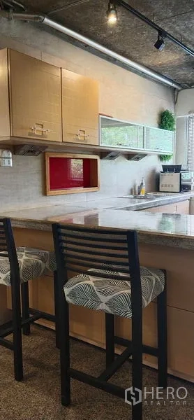 公寓 出售在Watthana, Bangkok - 厨房带早餐吧台，花岗岩台面、两把吧椅与吊柜。