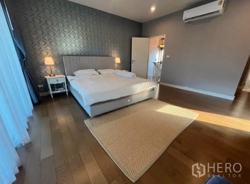 Detached House for rent in Prawet, Bangkok - Spacious master suite angle showing bed, air conditioner and feature wallpaper.