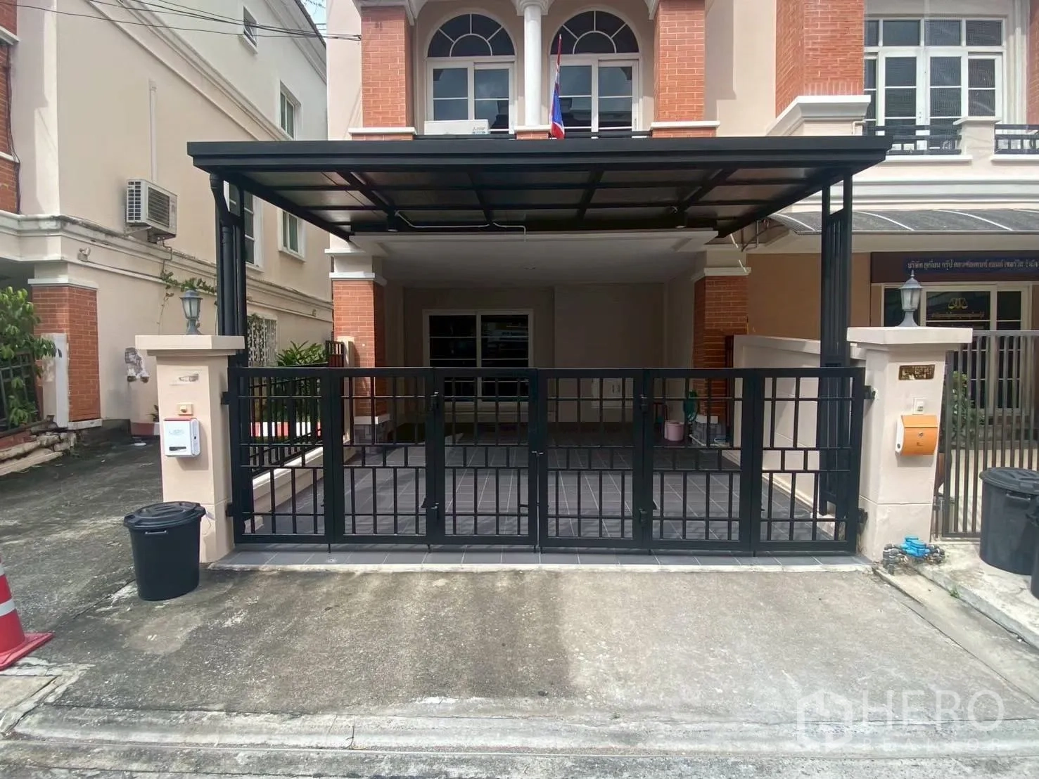 Townhouse for rent in Bang Kapi, Bangkok - Gated townhouse entrance with covered carport and tiled driveway.