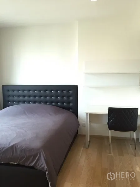 公寓 出租在Khlong Toei, Bangkok - 温馨卧室，软包床头、书桌与椅子，浅色木地板。